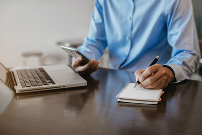 Midsection of man using mobile phone on table