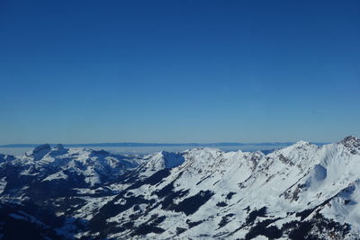 Scenic view of snowcapped mountains against blue sky