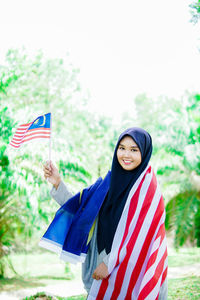 Muslim woman happy holding a malaysian flag. malaysia independence day.