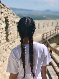Rear view of woman on footbridge against sky
