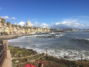 View of buildings by sea against sky in city