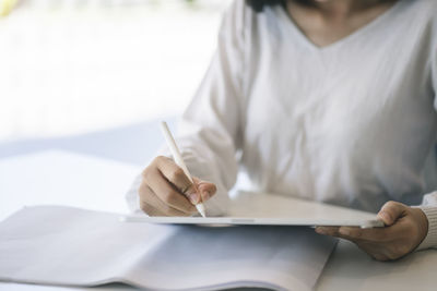 Midsection of woman reading book on table