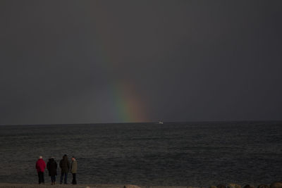 Rear view of people on beach against sky