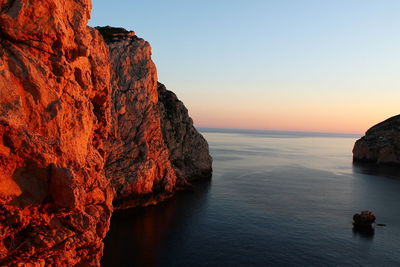 Rock formation in sea against clear sky