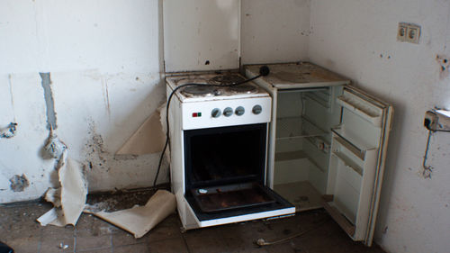 High angle view of abandoned stove and refrigerator in kitchen at home