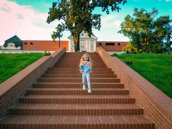 Full length of little girl on sidewalk against sky