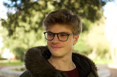 Close-up of smiling boy looking away against tree