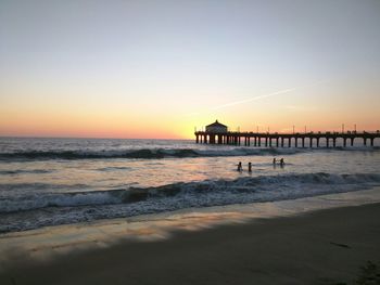 Scenic view of beach against clear sky during sunset