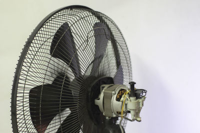 Low angle view of electric fan against wall