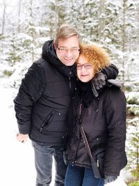 Portrait of couple standing against trees during winter