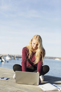 Full length of high school girl using laptop on pier