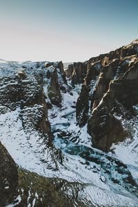 Scenic view of river flowing amidst snow covered mountains against sky