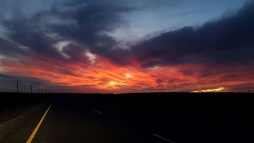 Road passing through landscape against cloudy sky