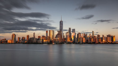 Illuminated buildings in city against cloudy sky
