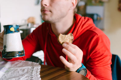 Midsection of man drinking glass on table