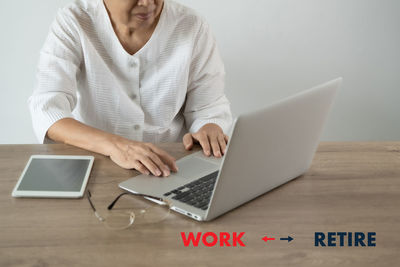 Midsection of woman using mobile phone while sitting on table