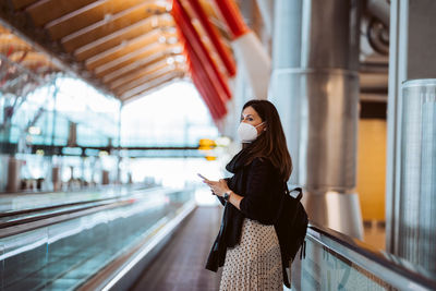 Side view of woman wearing mask standing at airport