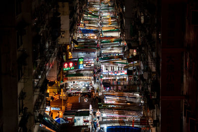 Illuminated street amidst buildings in city at night