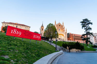 Information sign on road by building against sky