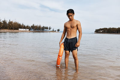 Shirtless man standing in water