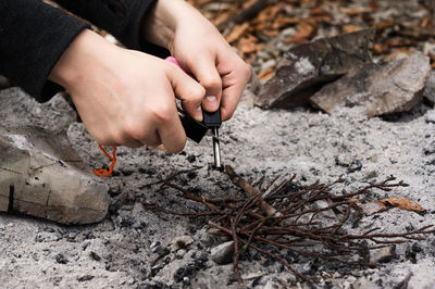 Cropped hands of woman igniting plants in forest