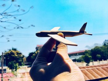 Close-up of person holding toy plane against sky