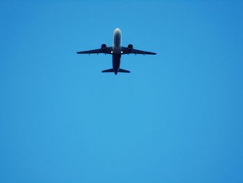 Low angle view of airplane against clear blue sky