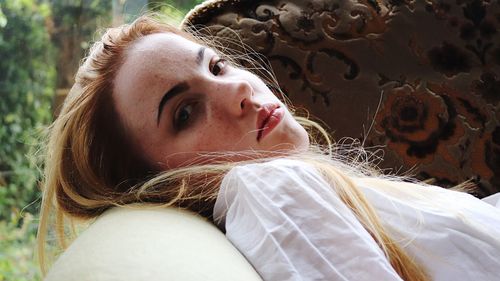 Close-up portrait of young woman lying down on sofa at home