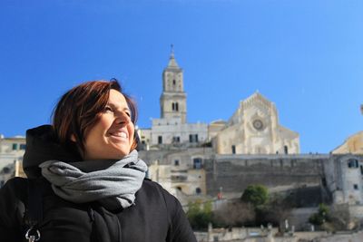 Portrait of smiling young woman against building