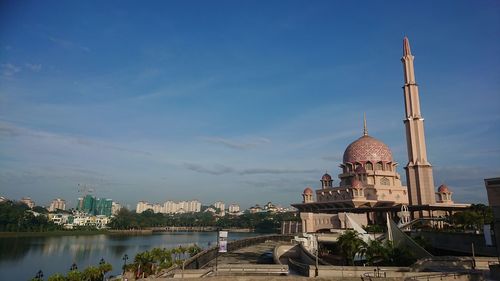 View of buildings by river in city against sky