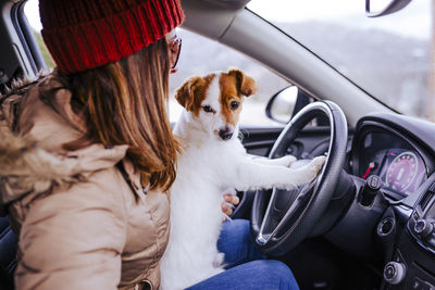 Side view of woman sitting with dog in car