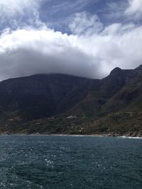 Scenic view of sea and mountains against cloudy sky