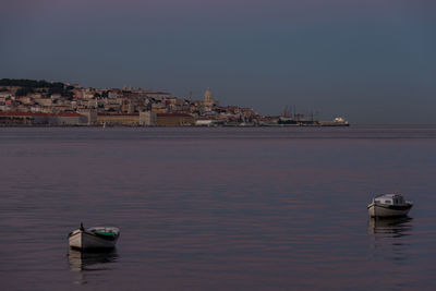 Sailboats in sea against buildings in city