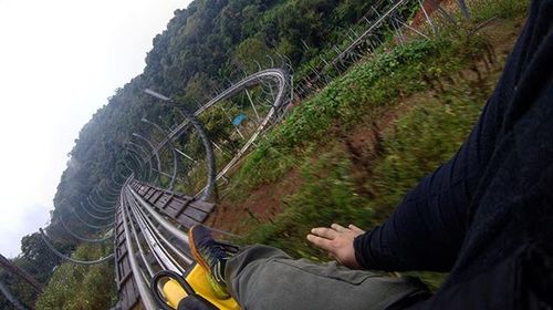 Low section of man sitting on mountain against sky