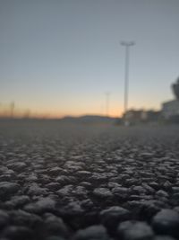 Surface level of snowy field against sky during sunset