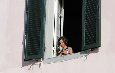 Low angle portrait of girl standing in window