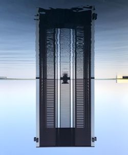 Reflection of building on sea against sky