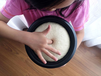 Directly above view of girl poking finger in dough at home