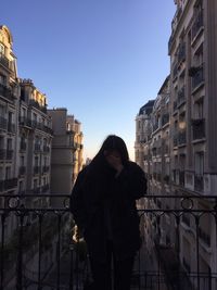 Woman standing on footbridge in city