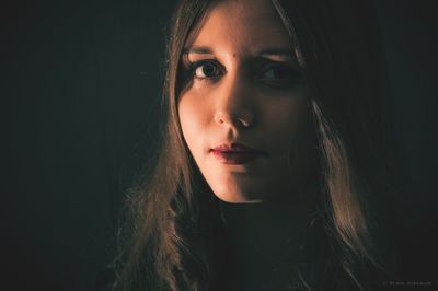 Close-up portrait of a beautiful young woman over black background