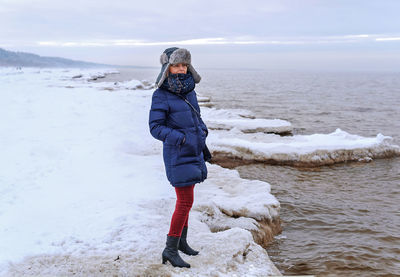 Woman standing on the snowy shore of the baltic sea.