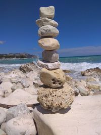 Stack of stones on beach against sky