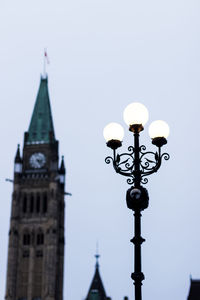 Low angle view of street light by building against sky