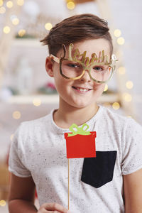 Portrait of smiling boy with prop at home during christmas