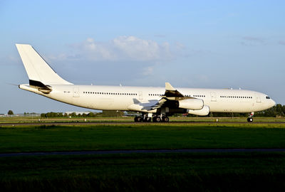 Airplane on airport runway against sky