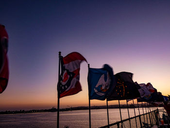 Low angle view of flags against clear sky during sunset