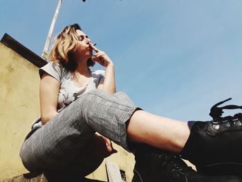 Young woman sitting against sky