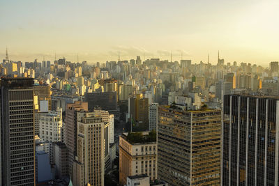 Aerial view of buildings in city against sky during sunset