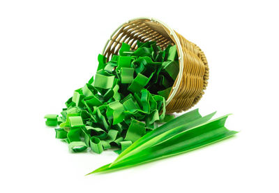 Close-up of leaf vegetable with basket against white background