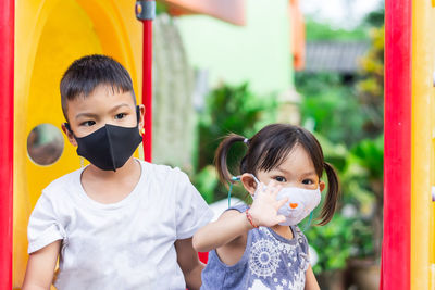 Portrait of siblings wearing masks playing in playground